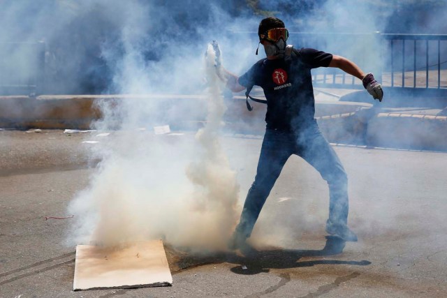 An anti-government protester throws a teargas canister back at the police in Caracas