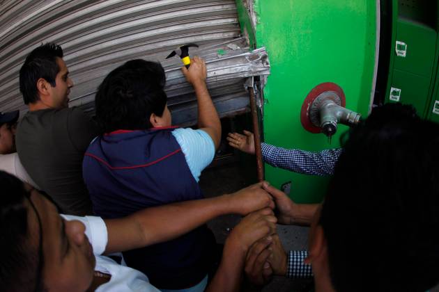 Supermarket employees try to fix a roller shutter at their workplace, which was damaged by Ayotzinapa Teacher Training College students, in Chilpancingo, in the Mexican state of Guerrero