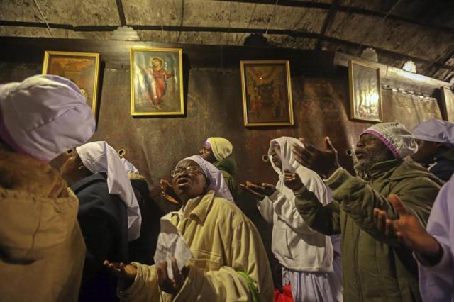 Un grupo de cristianos llegados de Nigeria rezan en la gruta que alberga la iglesia de la Natividad, lugar en el que la tradición sitúa el nacimiento de Jesucristo, en la ciudad palestina de Belén, hoy, 24 de diciembre de 2014. Miles de peregrinos de todo el mundo se encuentran en Belén para conmemorar la Nochebuena. EFE/Jim Hollander