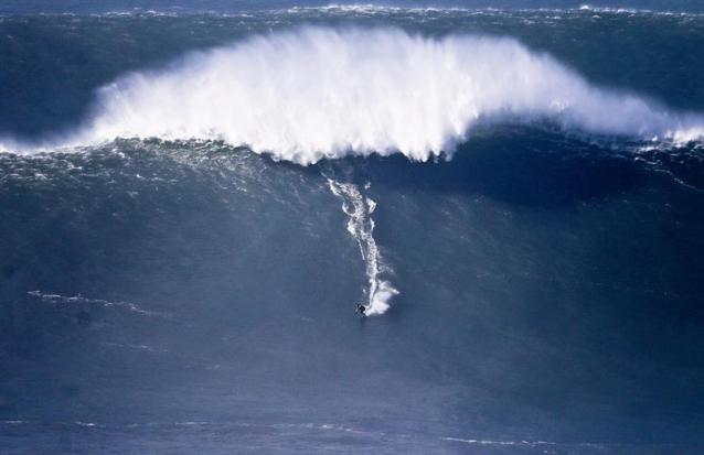 Un surfista surca una gran ola en Praia do Norte, Nazaré, Portugal, hoy, jueves 11 de diciembre de 2014. El temporal en la zona de los últimos tres días facilita las condiciones para la aparición de grandes olas en Nazaré, lugar en el que el surfista estadounidense Garret McNamara batió un récord mundial al surfear una ola de 30 metros en enero de 2013. EFE/Miguel A. Lopes