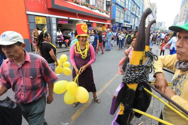 En la imagen se ve a una mujer vendiendo globos amarillos para celebrar el fin de año en una calle del centro de Lima (Perú). Durante las fiestas del Año Nuevo, el amarillo se convierte en el tono predominante en Lima, una ciudad donde ese color es usado para convocar la buena suerte y dejar atrás las penas del año anterior, que también son conjuradas con la quema de muñecos que representan a conocidos personajes nacionales. EFE/Paolo Aguilar