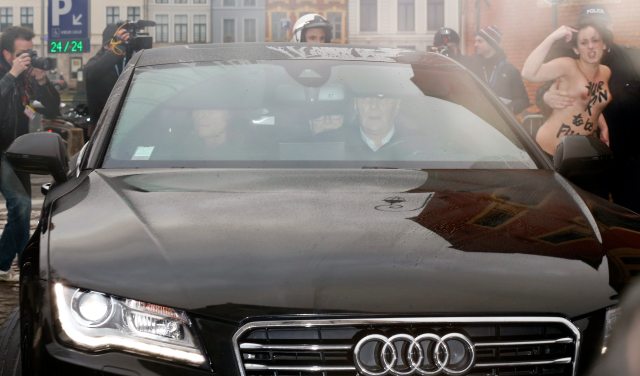 Police remove from the scene a topless activist of women's rights group FEMEN as former IMF head Strauss-Kahn rides with his lawyer Leclerc in backseat of a car as he arrives to attend trial in so-called "Carlton Affair", in Lille