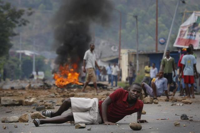 Manifestantes burundeses se enfrentan a oficiales de policía durante una manifestación antigubernamental hoy, miércoles 20 de mayo de 2015, en Buyumbura (Burundi). El presidente de Burundi, Pierre Nkurunziza, ha ordenado retrasar diez días las elecciones municipales y legislativas previstas inicialmente para el próximo día 26, según un decreto hecho público hoy. El pasado 25 de abril, el presidente Nkurunziza anunció que volvería a presentarse a las presidenciales de junio para optar a un tercer mandato, a pesar de que la Constitución limita a dos periodos de cinco años la duración del ejercicio de ese cargo. La decisión de mantener su candidatura desencadenó una ola de violentas protestas en las que han muerto al menos 20 civiles y 12 soldados acusados de dar un fallido golpe de Estado contra el presidente la pasada semana. EFE/Dai Kurokawa