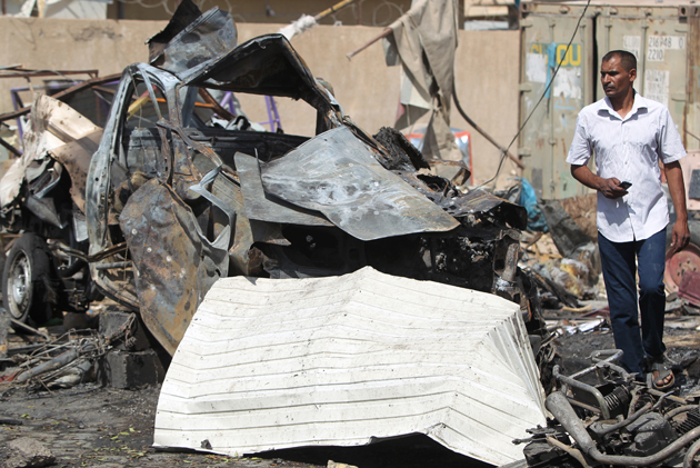 An Iraqi man walks past the wreckage of cars in the aftermath of a massive suicide car bomb attack carried out by the Islamic State group in the predominantly Shiite town of Khan Bani Saad, 20 km north of Baghdad, on July 18, 2015. The suicide attack by the IS group was one of the deadliest since it took over swathes of Iraq last year and came as the country marked Eid al-Fitr, the Muslim feast that ends the fasting month of Ramadan. AFP PHOTO / AHMAD AL-RUBAYE