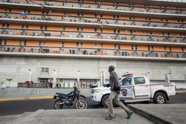 Un hombre camina frente al lugar donde autoridades realizan un nuevo operativo que hace parte de la llamada Operación de Liberación del Pueblo contra la inseguridad (OLP) hoy, miércoles 29 de julio de 2015, en las las residencias de la Misión Vivienda, en Caracas (Venezuela). La inseguridad es uno de los principales problemas en Venezuela y, según cálculos de la fiscal general, Luisa Ortega Díaz, la tasa de homicidios en el país en 2014 fue de 62 asesinatos por 100.000 habitantes, cifra que asciende a 82 para la organización no gubernamental Observatorio Venezolano de Violencia. EFE/Miguel Gutiérrez