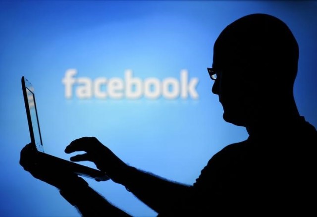 Un hombre junto a un fondo con el logo de Facebook en Zenica, Bosnia, 14 de agosto de 2013. Facebook está intentando atraer a escépticos anunciantes en la India con atractivas ofertas, como respaldo gratuito por correo electrónico para cuestiones sobre publicidad y asesoría para incrementar ventas, en un intento por elevar sus ingresos en su segundo mercado más grande en el mundo. REUTERS/Dado Ruvic/Files