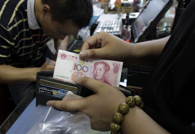 RO2 PEKÍN (CHINA), 13/08/2015.- Un cliente saca un billete de 100 yuanes en una tienda de Pekín, China, hoy, 13 de agosto de 2015. El Banco Popular de China (central) dio hoy por concluido el ajuste en el valor del yuan, después de rebajar durante tres jornadas consecutivas el tipo de cambio de referencia de la divisa asiática. EFE/ROLEX DELA PENA