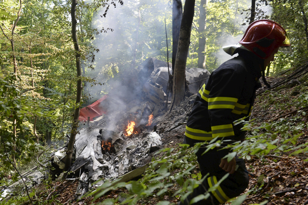 A firefighter inspects the crash site of two sport planes near the village of Cerveny Kamen, Slovakia, August 20, 2015. The death toll from the mid-air collision between the two sport planes over western Slovakia has risen to seven, according to a fire department spokesman.  REUTERS/Radovan Stoklasa