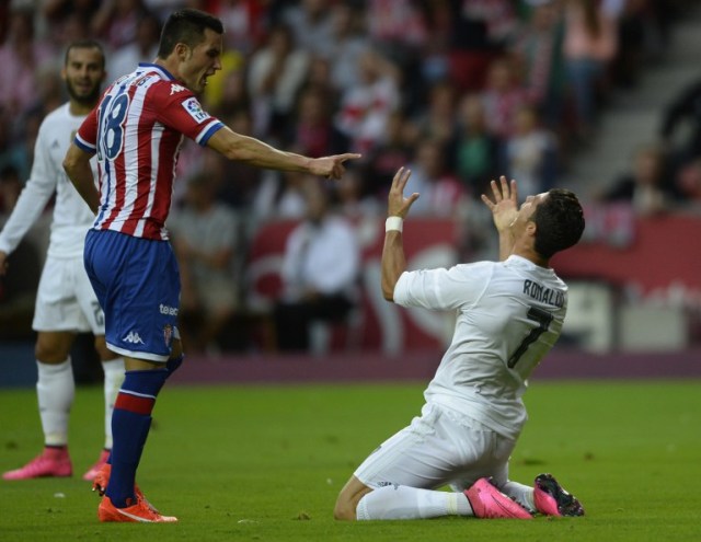 CORRECTION LEFT PLAYER'S NAME IN CAPTION Real Madrid's Portuguese forward Cristiano Ronaldo (R) reacts next to Sporting Gijon's forward Ismael Lopez during the Spanish league football match Sporting Gijon vs Real Madrid CF at the El Molinon stadium in Gijon on August 23, 2015.   AFP PHOTO/ MIGUEL RIOPA