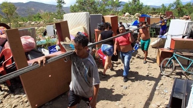 Cientos de colombianos cargan sus pertenencias por el río Táchira desde Venezuela hacia Colombia