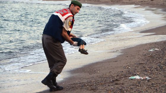 Un policía recoge el cadáver de un niño en una playa de Turquía.AP