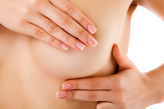 Woman examining her breast isolated on white