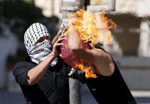 Un palestino intenta ayudar a un compañero que se ha prendido fuego al lanzar un cóctail molotov contra soldados israelíes durante una protesta en Hebrón (Palestina) hoy, 13 de octubre de 2015. Los ataques y disturbios de los últimos trece días se han cobrado la vida de siete israelíes y 29 palestinos, una decena de estos supuestos autores de ataques y el resto en disturbios y enfrentamientos con las fuerzas de seguridad en Jerusalén Este, Cisjordania y Gaza / EFE