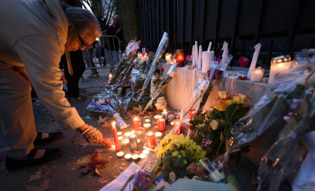 A women lights a candle next to flowers at a makeshift memorial at the French Consulate on November 14, 2015 in Geneva a day after deadly attacks in Paris. At least 128 people were killed in the Paris attacks on the evening of November 13, with 180 people injured, 80 of them seriously, police sources told. AFP PHOTO / FABRICE COFFRINI