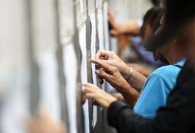 Citizens look for their names in the electoral roster at a polling station in Caracas, on December 6, 2015 during the Venezuela's legislative election. For the first time in 16 years of "Bolivarian revolution" under late president Hugo Chavez and his successor Nicolas Maduro, polls show their rivals could now win a majority in the National Assembly. AFP PHOTO/ JUAN BARRETO / AFP / JUAN BARRETO