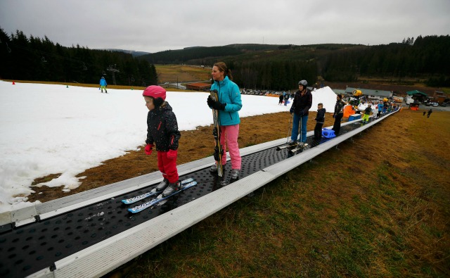 Los visitantes se mueven hacia arriba a lo largo de una pista hecha con nieve artificial por un cañón de nieve durante el clima cálido en el oeste de Alemania estación de esquí de Winterberg alguna sureste 80 kilometros de Dortmund, Alemania 22 de diciembre de 2015. REUTERS / Wolfgang Rattay