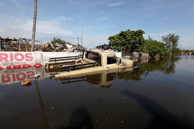 Vista de un vehículo cubierto por agua en un barrio de Asunción (Paraguay) hoy, lunes 28 de diciembre de 2015. Por las crecidas de los ríos Paraguay y Paraná, la ciudad del país más castigada por la crecida es Asunción, donde hay unos 90.000 evacuados, según la municipalidad capitalina, aunque la Secretaria de Emergencia Nacional cifra en 70.000 el número de desplazados. La mayoría de esos damnificados viven en espacios proporcionados por el Gobierno desde que comenzara a subir el río, que de momento se mantiene en los 7,8 metros de altura. EFE/Andrés Cristaldo Benítez