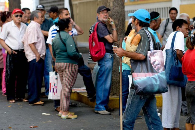 TO GO WITH AFP STORY by Valentina Oropeza and Ernesto Tovar People queue at a bakery in Caracas on February 25, 2016. On any given day, people in Venezuela can wait hours to get some subsidized milk, cooking oil, milk or flour -- if they can find any -- with some bakeries rationing their bread production and others selling no bread at all. Venezuela, which is sitting on the biggest known oil reserves from which it derives 96 percent of its foreign revenues, has been devastated by the drop in prices and is beset with record shortages of basic goods, runaway inflation and an escalating economic crisis. AFP PHOTO / FEDERICO PARRA / AFP / FEDERICO PARRA