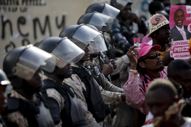 National Police officers stand guard next to the Provisional Electoral Council building as supporters of PHTK political party attend a speech during a demonstration demanding the organization of a postponed presidential runoff election in Port-au-Prince, Haiti, April 24, 2016. April 24 REUTERS/Andres Martinez Casares