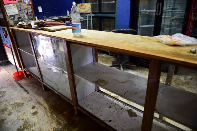 Picture taken inside a minimarket that was looted during the early morning at the poor neighbourhood of Petare in Caracas on June 10, 2016. Venezuela President Nicolas Maduro faces mounting protests over shortages of food, medicine, electricity and water. / AFP PHOTO / RONALDO SCHEMIDT