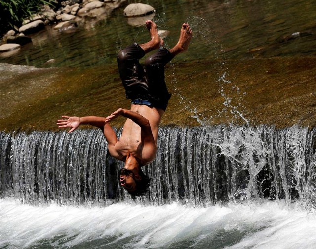 Un chico salta sobre una cascada para combatir el calor a las afueras de Srinagar, Cachemira, India, hoy, 14 de junio de 2016. El tiempo es cada vez más caluroso en la región india de Cachemira cuando los musulmanes celebran el mes sagrado del Ramadán. EFE/Farooq Khan