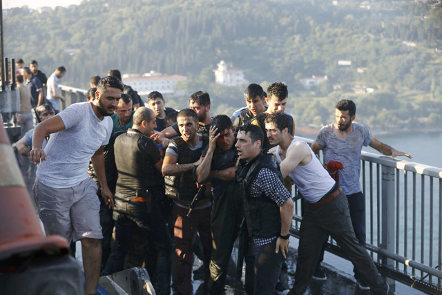 Policemen protect a soldier from the mob after troops involved in the coup surrendered on the Bosphorus Bridge in Istanbul, Turkey July 16, 2016. REUTERS/Murad Sezer