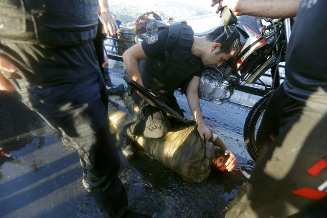 A policeman checks a slodier beaten by the mob after troops involved in the coup surrendered on the Bosphorus Bridge in Istanbul, Turkey July 16, 2016. REUTERS/Murad Sezer