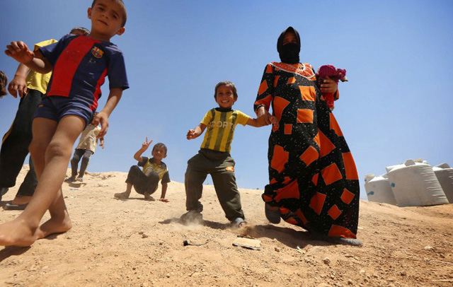 An Iraqi displaced woman and children, who fled the violence in the northern city of Mosul, walk at the Dibaga camp on July 16, 2016 in Makhmur, about 280 kilometres (175 miles) north of the capital Baghdad. / AFP PHOTO / SAFIN HAMED