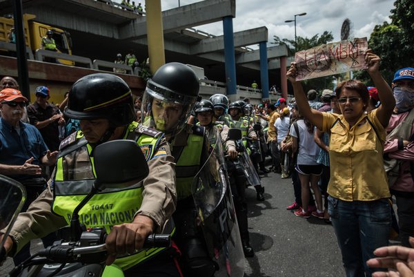 Un manifestante en Caracas llevó a cabo un cartel diseñado para parecerse a un billete de 100 bolívares, con "hambre" escrito en él en español, ya que la policía intentó disolver una manifestación en junio. MERIDITH KOHUT PARA THE NEW YORK TIMES