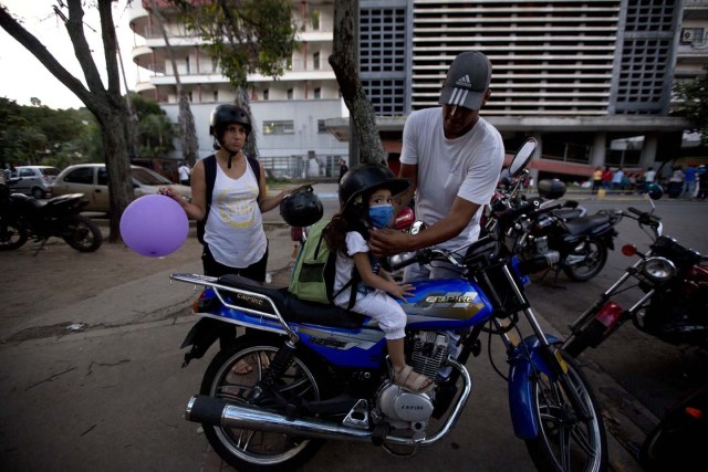 En esta imagen, tomada el 19 de septiembre de 2016, Maykol Pacheco, coloca un casco a su hija Ashley mientras se preparan para salir del hospital universitario de Caracas, Venezuela. Dos semanas después de sufrir un raspón en la rodilla, la niña se retorcía de dolor en la cama de un hospital. Le costaba respirar e imploraba a sus padres que le llevasen agua. (AP Foto/Fernando Llano)