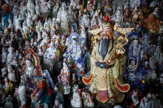 This picture taken on August 9, 2016 shows a display of unwanted statues of deities, gathered and repaired after their owners discarded them, on a rocky slope running down to the sea in Hong Kong. Religion and local customs permeate Hong Kong, where Buddhist and Taoist temples are common and incense offerings are regularly burned outside local businesses. Private homes often have a shrine to a local deity, with Christian churches and mosques also in the mix. But with space at a premium in a city were rents are sky high, informal collections of discarded gods often decorate roadsides and public spaces. / AFP PHOTO / Anthony WALLACE / To go with "HONG KONG-CULTURE-LIFESTYLE-RELIGION", FEATURE by Dennis Chong