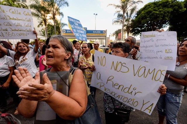 People shout slogans in demand of the referendum on removing President Nicolas Maduro, as the opposition Democratic Unity Roundtable (MUD) coalition offers a press conference in Caracas on October 21, 2016. A furious Venezuelan opposition Friday vowed mass protests, accusing the Socialist government of staging a coup by blocking its drive for a recall referendum against President Nicolas Maduro. The MUD called for nationwide demonstrations from next Wednesday against the decision to annul a key stage in the referendum process. / AFP PHOTO / Federico PARRA