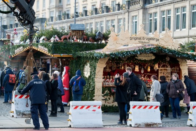 A policeman places concrete elements in front of the "Striezelmarkt" Christmas market in Dresden, eastern Germany, on December 20, 2016, as security measures are taken after a deadly rampage by a lorry driver at a Berlin Christmas market. German Chancellor Angela Merkel said that authorities believe the rampage, killing 12, was a "terrorist" attack likely committed by an asylum seeker. / AFP PHOTO / dpa / Arno Burgi / Germany OUT