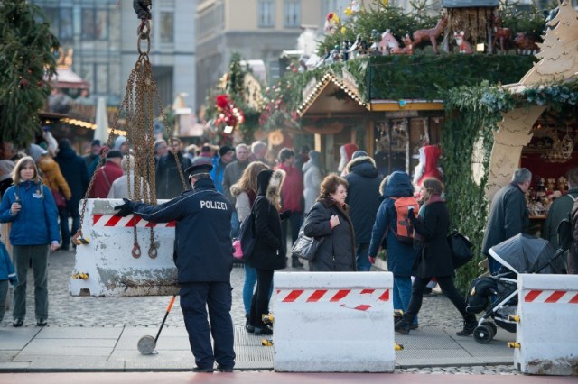 A policeman places concrete elements in front of the "Striezelmarkt" Christmas market in Dresden, eastern Germany, on December 20, 2016, as security measures are taken after a deadly rampage by a lorry driver at a Berlin Christmas market. German Chancellor Angela Merkel said that authorities believe the rampage, killing 12, was a "terrorist" attack likely committed by an asylum seeker. / AFP PHOTO / dpa / Arno Burgi / Germany OUT