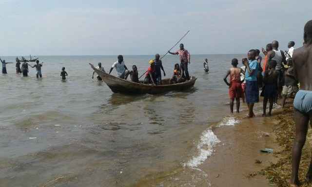 Rescuers are seen on a fishing boat on Lake Albert, on December 26, 2016 in Buliisa, after at least 30 Ugandan members of a village football team and their fans drowned when their boat capsized on Lake Albert during a party. Police officers working with local fishermen managed to rescue 15 of the revellers, who were heading from the village of Kaweibanda in the western Buliisa District to watch a friendly Christmas Day match in Hoima District, Rutagira said. / AFP PHOTO / -