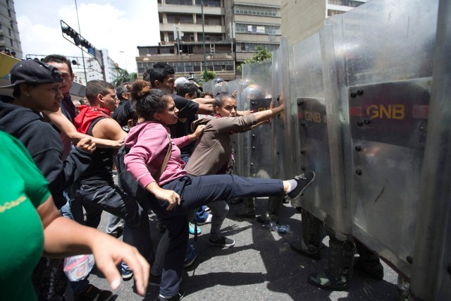 En esta imagen de archivo, tomada el 2 de junio de 2016, una mujer patea escudos de soldados de la Guarda Nacional durante una protesta para exigir comida, cerca del palacio presidencial de Miraflores, en Caracas, Venezuela, provocada por la creciente frustración por la escasez de comida y la inflación. El presidente, Nicolás Maduro, ha ampliado de forma considerable el poder de los generales, que se han convertido en un apoyo fundamental mientras la economía se hunde y crecen las protestas callejeras contra un gobierno tremendamente impopular. (AP Foto/Ariana Cubillos, archivo)