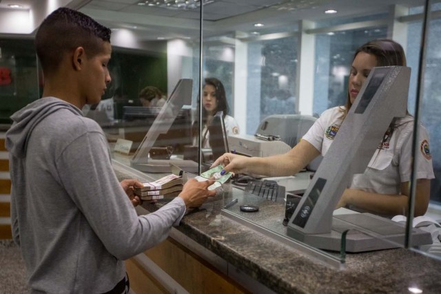 CAR13. CARACAS (VENEZUELA), 16/01/2017.- Trabajadores de un banco manipulan billetes del nuevo cono monetario hoy 16 de enero de 2017, en Caracas (Venezuela). Los billetes de 500, 5.000 y 20.000 bolívares, tres de las seis piezas que conforman el nuevo cono monetario, comenzaron a circular hoy en Venezuela tal y como lo aseguró ayer el presidente, Nicolás Maduro, y un mes más tarde de lo previsto inicialmente debido a un "sabotaje internacional". EFE/Miguel Gutiérrez