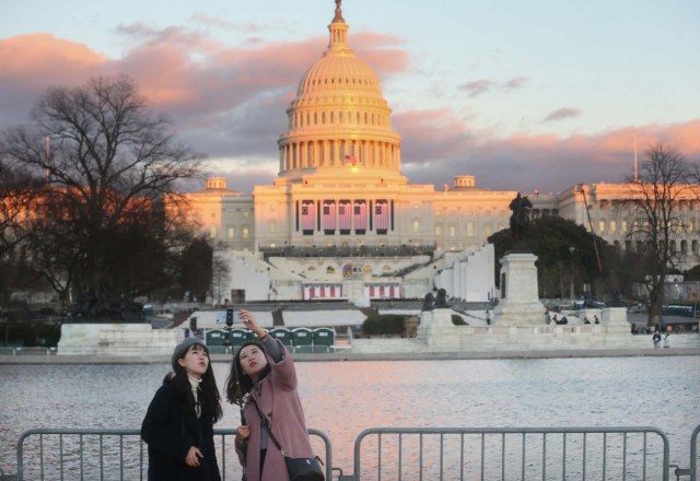 WASHINGTON, DC - JANUARY 18: PEople take photos as the sun sets on the West Front of the U.S. Capitol building ahead of inauguration ceremonies there for President-elect Donald Trump on January 18, 2017 in Washington, DC. Trump will be sworn in as the 45th U.S, president on January 20.   Mario Tama/Getty Images/AFP