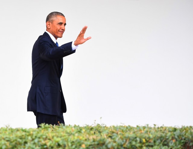 US President Barack Obama waves as he walks through the colonnade as he departs the Oval Office for the last time as president, at the White House in Washington, DC January 20, 2017. / AFP PHOTO / JIM WATSON