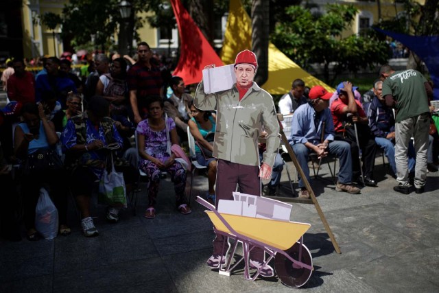 A cardboard cut-out of Venezuela's late President Hugo Chavez is seen as people wait to apply for a card that will register them for government social programmes