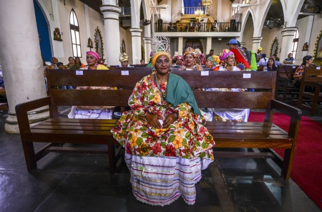 Women dressed as "madamas" attend a mass before the beginning of the Carnival in El Callao, in Bolivar state, Venezuela on February 26, 2017. El Callao's carnival was recently named Unesco's Intangible Cultural Heritage of Humanity and is led by the madamas, the pillars of Callaoense identity representing Antillean matrons considered the communicators of values, who dance and wear colourful dresses. / AFP PHOTO / JUAN BARRETO