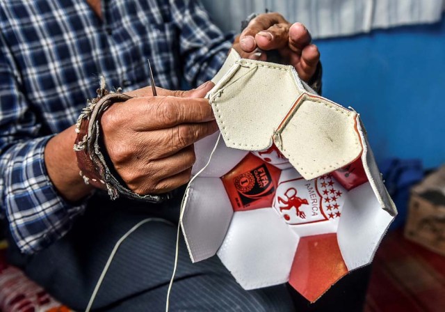 Worker Jose Sierra sews a football by hand at a ball factory in Mongui, in the Colombian department of Boyaca, on February 13, 2017. Mongui, in the central mountains of Colombia, has about 20 ball factories that make balls mainly for football and micro-football. About a quarter of the town's 4,900 inhabitants work in these factories. / AFP PHOTO / Luis ACOSTA