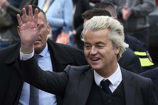 Dutch far-right Freedom Party leader (Partij Voor De Vrijheid, PVV) Geert Wilders waves as he arrives under police escort to speak to a crowd in Heerlen on March 11, 2017. Wilders was guarded by police as protesters took to the streets while he handed out pamphlets and posed for selfies as part of his election campaign. / AFP PHOTO / JOHN THYS