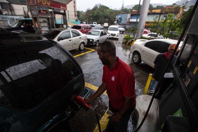 CAR308. CARACAS (VENEZUELA), 24/03/2017.- Un hombre llena el tanque de combustible de un vehículo hoy, viernes 24 de marzo de 2017, en una estación de gasolinaen Caracas (Venezuela). Decenas de estaciones de servicio en Venezuela amanecieron hoy con vehículos en cola para abastecerse de gasolina, luego de que la estatal Pdvsa reportara el pasado miércoles un retraso en el transporte de combustible y se registrasen fallos de suministro en al menos cuatro estados centrales. EFE/CRISTIAN HERNÁNDEZ