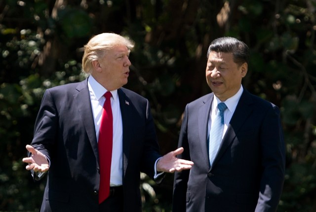 US President Donald Trump (L) and Chinese President Xi Jinping (R) walk together at the Mar-a-Lago estate in West Palm Beach, Florida, April 7, 2017. President Donald Trump entered a second day of talks with his Chinese counterpart Xi Jinping on Friday hoping to strike deals on trade and jobs after an overnight show of strength in Syria. / AFP PHOTO / JIM WATSON