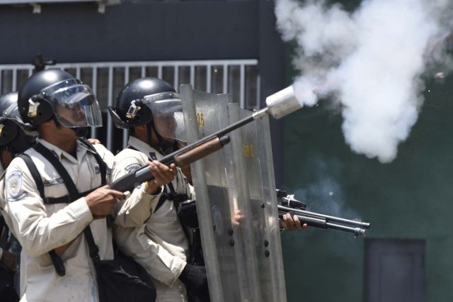 Riot police throw tear gas during clashes with demonstrators against Nicolas Maduro's government in Caracas on April 8, 2017. The opposition is accusing pro-Maduro Supreme Court judges of attempting an internal "coup d'etat" for attempting to take over the opposition-majority legislature's powers last week. The socialist president's supporters held counter-demonstrations on Thursday, condemning Maduro's opponents as "imperialists" plotting with the United States to oust him. / AFP PHOTO / JUAN BARRETO