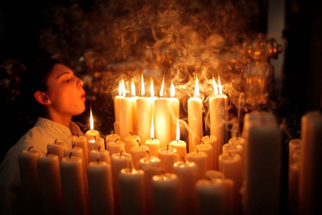A penitent of "Lagrimas and Favores" blows out candles inside a church as she takes part in a Palm Sunday procession, marking the start of the Holy Week in Malaga, southern Spain, April 9, 2017. REUTERS/Jon Nazca     TPX IMAGES OF THE DAY