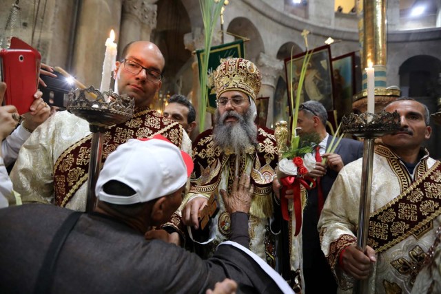 A man touches the Coptic Orthodox Bishop Anthony, during a Palm Sunday ceremony in the Church of the Holy Sepulchre in Jerusalem's Old City April 9, 2017. REUTERS/Ammar Awad