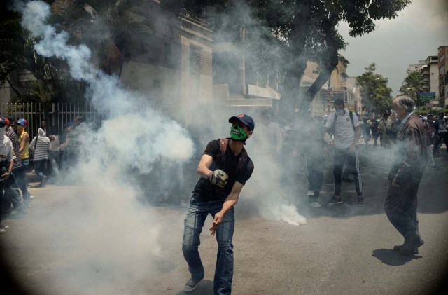 Demonstrators clash with the riot police during a protest against Venezuelan President Nicolas Maduro, in Caracas on April 20, 2017. Venezuelan riot police fired tear gas Thursday at groups of protesters seeking to oust President Nicolas Maduro, who have vowed new mass marches after a day of deadly unrest. Police in western Caracas broke up scores of opposition protesters trying to join a larger march, though there was no immediate repeat of Wednesday's violent clashes, which left three people dead. / AFP PHOTO / Federico PARRA