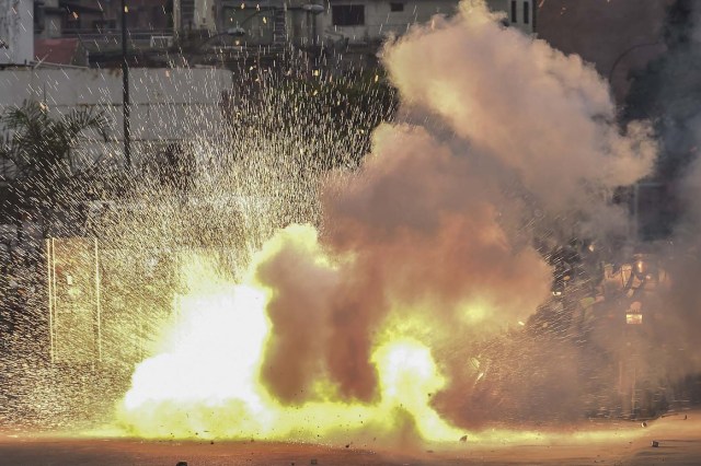 Demonstrators clash with the riot police during a protest against Venezuelan President Nicolas Maduro, in Caracas on April 20, 2017. Venezuelan riot police fired tear gas Thursday at groups of protesters seeking to oust President Nicolas Maduro, who have vowed new mass marches after a day of deadly unrest. Police in western Caracas broke up scores of opposition protesters trying to join a larger march, though there was no immediate repeat of Wednesday's violent clashes, which left three people dead. / AFP PHOTO / Ronaldo SCHEMIDT